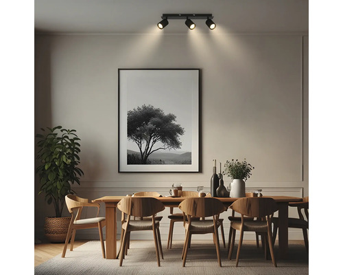 Dreiflammiger Deckenstrahler in einem modernen Esszimmer über einem Holztisch mit Stühlen und großem Wandbild.