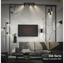 Modernes Wohnzimmer mit Beleuchtung der Briloner IDA-Serie, bestehend aus Deckenstrahlern, Stehlampe und Wandleuchten in Schwarz.
