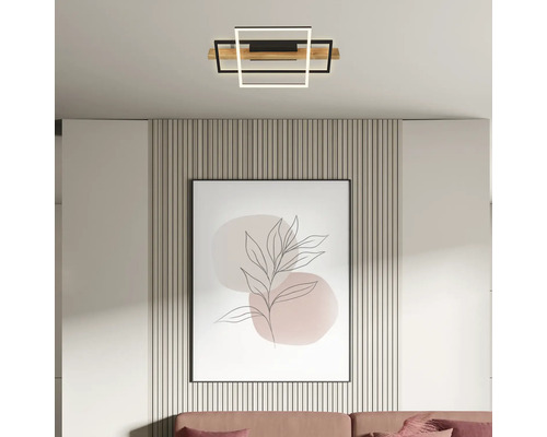 Moderne LED-Deckenleuchte mit geometrischen Quadraten aus Holz und Metall in einem hellen Wohnzimmer über einem eingerahmten Wandbild.