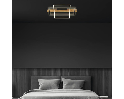 Moderne LED-Deckenleuchte in einem minimalistischen Schlafzimmer mit dunklen Wänden, Holzpaneelen und einem grauen Bett.