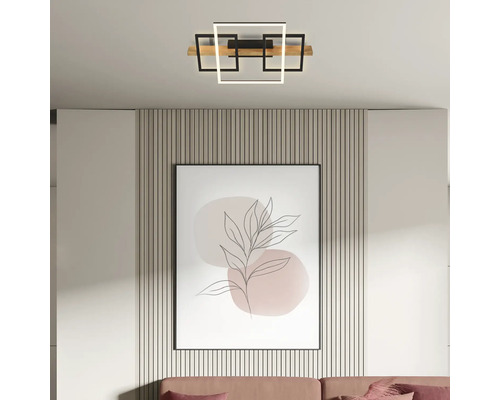 Moderne LED-Deckenleuchte mit geometrischen, quadratischen Rahmen und einem Holzelement, montiert in einem hellen, modern eingerichteten Raum.