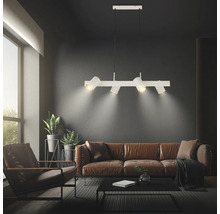 Weiße Pendelleuchte mit vier verstellbaren Strahlern in einem modernen Wohnzimmer mit braunem Ledersofa und dunklen Wänden.