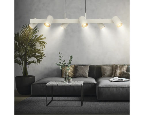 Moderne weiße Pendelleuchte mit sechs verstellbaren Strahlern über einem grauen Sofa im Wohnzimmer mit Marmortisch und Zimmerpflanze.