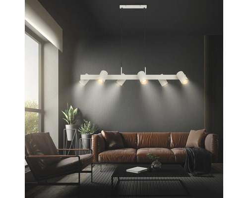 Moderne sechsflammige Pendelleuchte aus Metall mit verstellbaren Spots über einem Sofa im Wohnzimmer.
