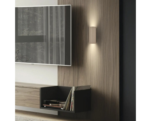 Moderne zylindrische Wandleuchte mit Rillen auf Holzpaneel im Wohnzimmer, Up-and-Down-Beleuchtung neben Fernseher.