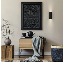 Moderner Innenraum mit schwarzer Wandleuchte, abstraktem Bild, Sideboard aus Holz, grauer Decke, Vase mit Zweigen und geflochtenem Korb.