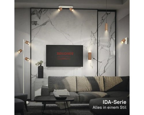 Modernes Wohnzimmer mit Lampen der Briloner IDA-Serie: Deckenstrahler, Pendelleuchte, Wandleuchte und Stehleuchte vor einer Marmorwand.