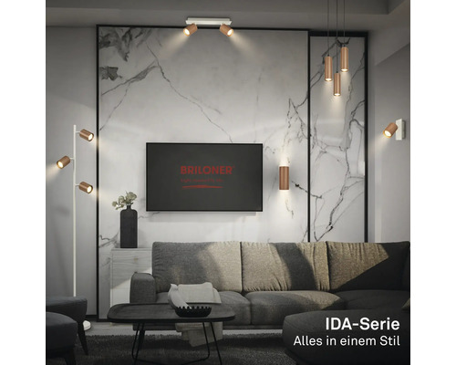 Modernes Wohnzimmer mit Leuchten der IDA-Serie von Briloner: Stehlampe, Deckenstrahler, Pendelleuchte und Wandleuchten in Holzoptik.