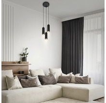 Modernes Wohnzimmer mit einer schwarzen dreiflammigen zylindrischen Pendelleuchte über einem großen beigen Ecksofa mit diversen Kissen.