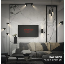 Modernes Wohnzimmer mit schwarzen Leuchten der Briloner IDA-Serie, darunter Stehleuchte, Pendelleuchten und Wandstrahler vor einer Marmorwand.