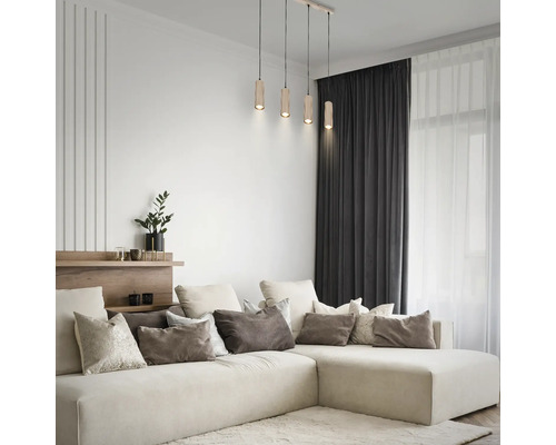 4-flammige Pendelleuchte mit zylindrischen Holzschirmen in einem hellen, modernen Wohnzimmer über einem großen Ecksofa mit Kissen.