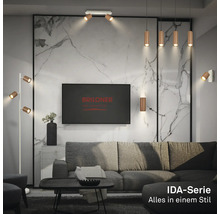 Modernes Wohnzimmer mit Metalllampen der Briloner IDA-Serie, grauem Sofa und Wand in Marmoroptik. Briloner Logo auf dem Fernseher.
