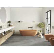 Modernes Badezimmer mit freistehender Badewanne, wandhängender Toilette und Bidet, Waschtischunterschrank aus Holz und grauen Bodenfliesen.