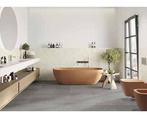 Modernes Badezimmer mit freistehender Badewanne, wandhängender Toilette und Bidet, Waschtischunterschrank aus Holz und grauen Bodenfliesen.