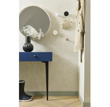 Modern gestalteter Flur mit blauem Konsolentisch, rundem Spiegel, schwarzen Gummistiefeln und Wandhaken an einer hellen, strukturierten Wand.