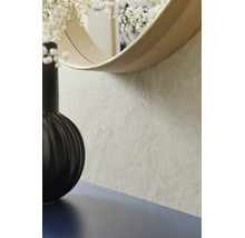 Nahaufnahme einer strukturierten Wand in Steinoptik mit einem runden Spiegel mit Holzrahmen und einer schwarzen Vase.