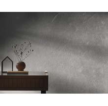 Moderne Wandgestaltung in grauer Betonoptik mit strukturiertem Putz, Holzkommode, runder Vase mit Trockenblumen und dekorativem Objekt.