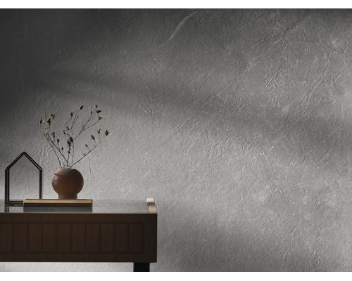 Moderne Wandgestaltung in grauer Betonoptik mit strukturiertem Putz, Holzkommode, runder Vase mit Trockenblumen und dekorativem Objekt.