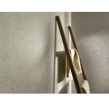 Strukturierte Wand in Steinoptik mit einer Handtuchleiter aus Holz und aufgehängten Handtüchern in einem modernen Badezimmer.