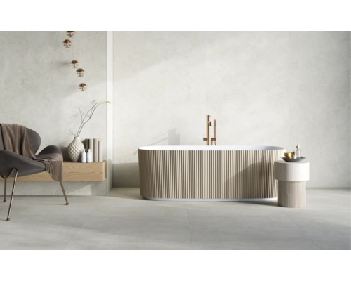 Freistehende Badewanne mit gerippter Außenwand, Standarmatur in Kupferoptik, Sessel und Dekoration in einem hellen, modernen Badezimmer.