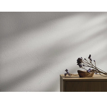 Strukturierte Wand mit Putzoptik, Holzkommode mit Holzschale und Trockenblumen, Lichteinfall mit Schatten.