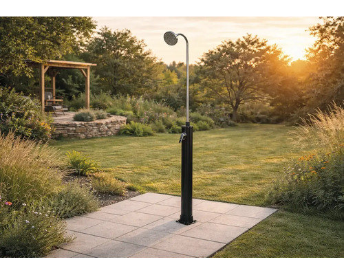 Solardusche im Garten auf Fliesen montiert, mit großem Duschkopf und Einhebelmischer, im Hintergrund Rasen und Gartenhaus.