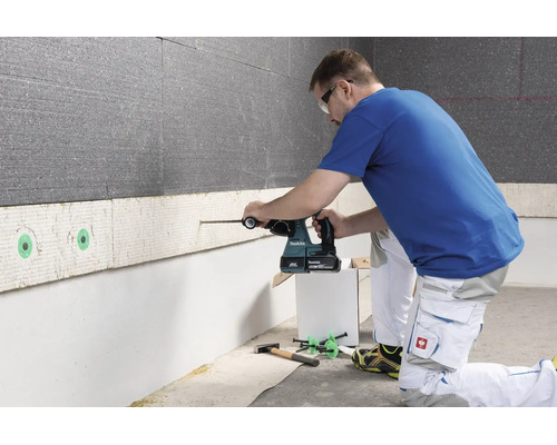 Eine Person bohrt mit einem Makita Akku-Bohrhammer in eine Wanddämmplatte.
