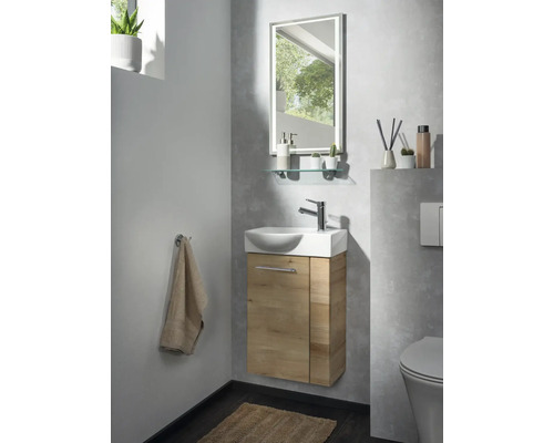 Modernes Gästebad mit kleinem Waschbecken, Unterschrank in Holzoptik, Chrom-Armatur und beleuchtetem Spiegel.