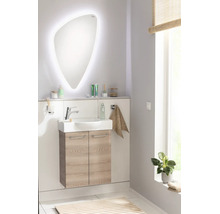 Modernes Badezimmer-Set bestehend aus einem organisch geformten LED-Spiegel, Keramikwaschtisch und hängendem Unterschrank in heller Eiche-Optik.