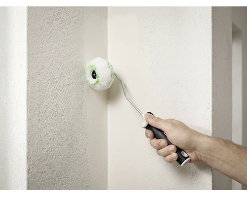Ein kleiner runder Eckenroller wird verwendet, um die Innenecke einer strukturierten weißen Wand zu streichen.