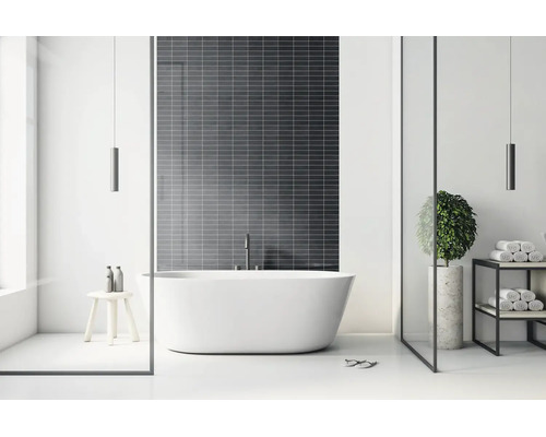 Modernes, helles Badezimmer mit freistehender Badewanne vor einer dunklen Fliesenwand, minimalistischem Regal und Holzhocker.