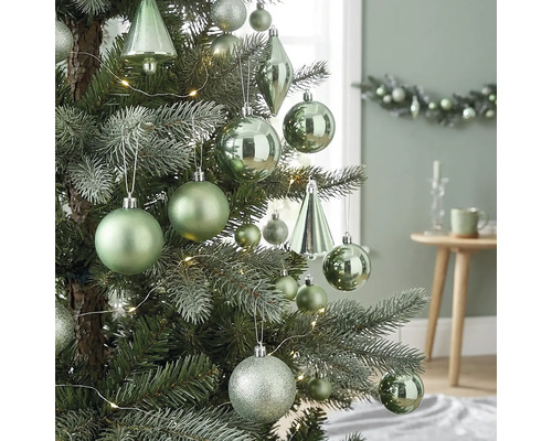 Weihnachtsbaum dekoriert mit matten, glänzenden und glitzernden Kugeln, tropfenförmigen Ornamenten und einer LED-Lichterkette in hellem Ambiente.