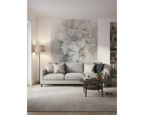 Modernes, helles Wohnzimmer mit grauem Sofa, dunklem Couchtisch und einer großflächigen Blumentapete an der Wand hinter dem Sofa.