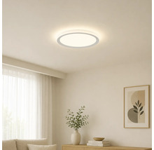 Flache, runde LED-Deckenleuchte in einem hellen, minimalistischen Wohnzimmer mit Holzmöbeln und Dekoration.