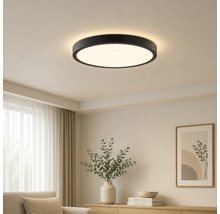 Moderne runde LED-Deckenleuchte mit schwarzem Rahmen in einem hellen Wohnzimmer.