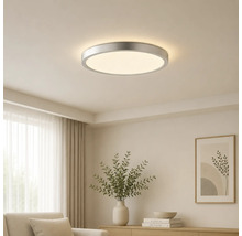 Runde LED-Deckenleuchte mit Metallrahmen, montiert an einer hellen Zimmerdecke in einem modern eingerichteten Wohnzimmer.