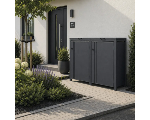 Moderne Mülltonnenbox aus Metall für zwei Tonnen im Vorgarten mit gepflastertem Weg und Pflanzen neben einem Hauseingang.