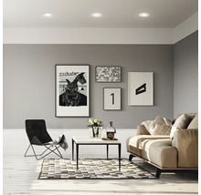 Modernes Wohnzimmer mit Einbaustrahlern in der Decke, Sofa, Couchtisch und Wandbildern.