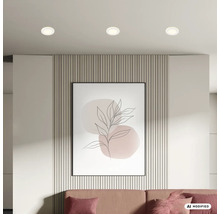 Drei runde Deckeneinbauleuchten strahlen von der Decke über einem modernen Wohnbereich mit Wandpaneelen und abstraktem Wandbild.