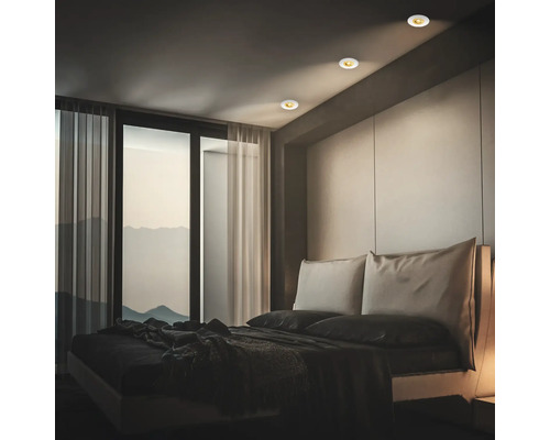 Modernes Schlafzimmer mit Einbaustrahlern in der Decke für akzentuierte Beleuchtung und Blick auf eine Berglandschaft.