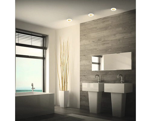 Modernes Badezimmer mit Doppelwaschtisch, Einbaustrahlern in der Decke, Badewanne und Wandverkleidung in Holzoptik.