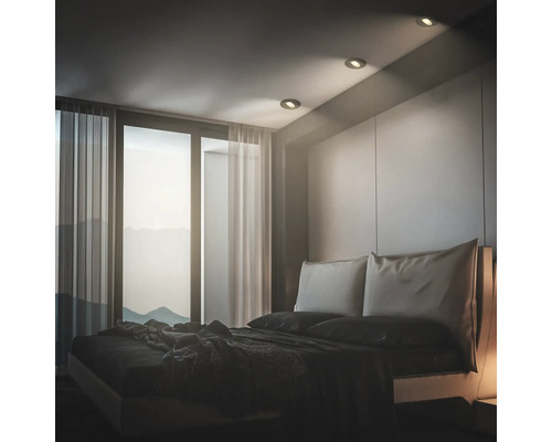 Modernes Schlafzimmer mit Einbaustrahlern in der Decke, bodentiefen Fenstern und bequemen Doppelbett in minimalistischer Innenraumgestaltung.