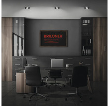 Modernes Büro mit Schreibtisch, zwei Bürostühlen, Schrankwand und drei Deckenleuchten sowie Briloner Logo an der Wand.