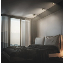 Modernes Schlafzimmer mit Einbaustrahlern in der Decke, bodentiefen Fenstern und bequemen Doppelbett in minimalistischer Innenraumgestaltung.