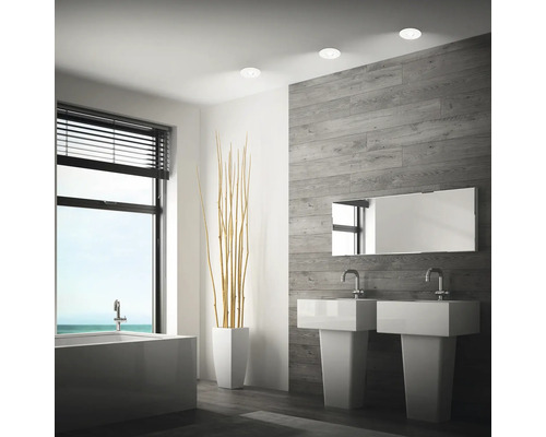 Modernes Badezimmer mit zwei Waschbecken, Badewanne, Wandverkleidung in Holzoptik und Einbaustrahlern an der Decke.