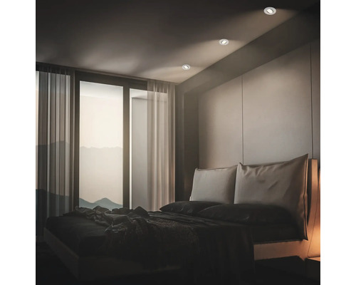 Modernes Schlafzimmer mit runden Deckeneinbaustrahlern, die für eine dezente Beleuchtung des Raumes und des Doppelbettes sorgen.
