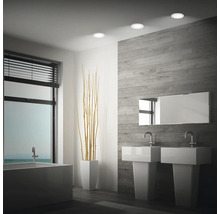 Modernes Badezimmer mit zwei Waschbecken, Badewanne, holzoptischer Wandverkleidung und drei runden LED Einbaustrahlern an der Decke.