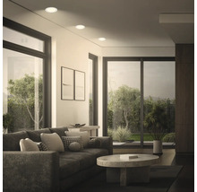 Modernes Wohnzimmer mit Einbaustrahlern in der Decke, geräumiges Design mit bodentiefen Fenstern und Blick in einen begrünten Garten.