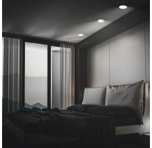 Modernes Schlafzimmer mit Einbaustrahlern in der Decke, bodentiefen Fenstern und Blick auf Berge bei Dämmerung.