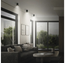 Modernes Wohnzimmer mit runden Deckenstrahlern, die für eine helle und punktuelle Beleuchtung sorgen, mit Sofa und Couchtisch.
